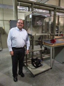 Doug Zentz, associate professor and program chair of Ferris State's HVACR department, poses with a miniature refrigerator that all freshman students are required to build.